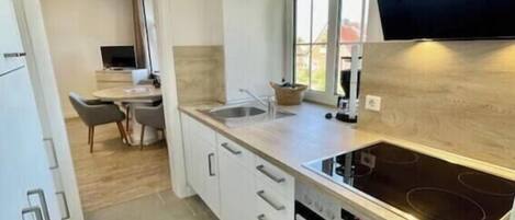 A modern kitchen with a built-in oven, a stovetop, and a window above the sink.