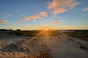 A sunset over a sandy landscape with bicycles parked along a path. - old officers' house 3 (Borkum)