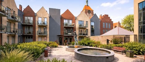 A courtyard with a fountain, benches, and a statue.