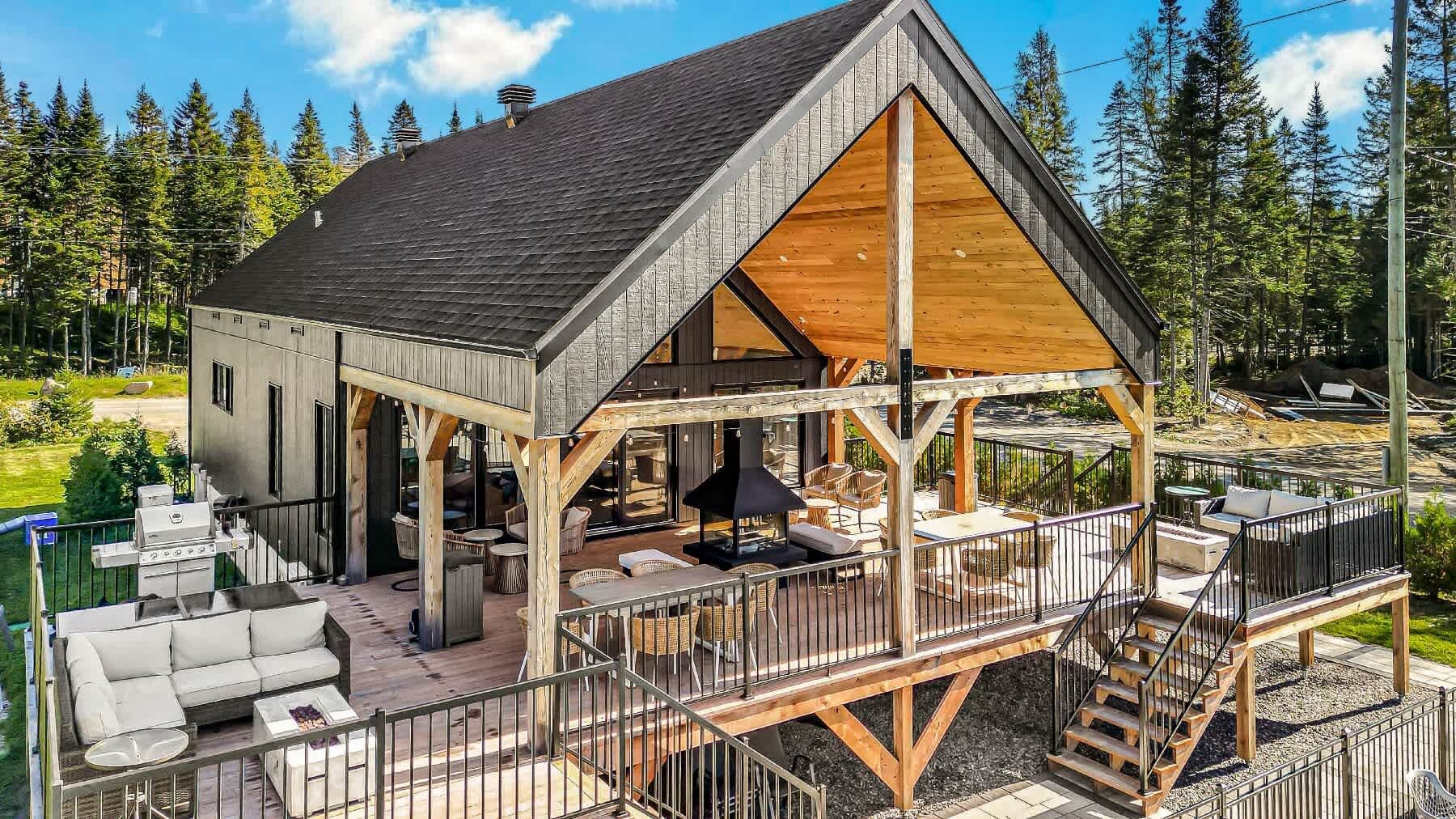 A cabin with a deck, outdoor seating, and a fireplace.