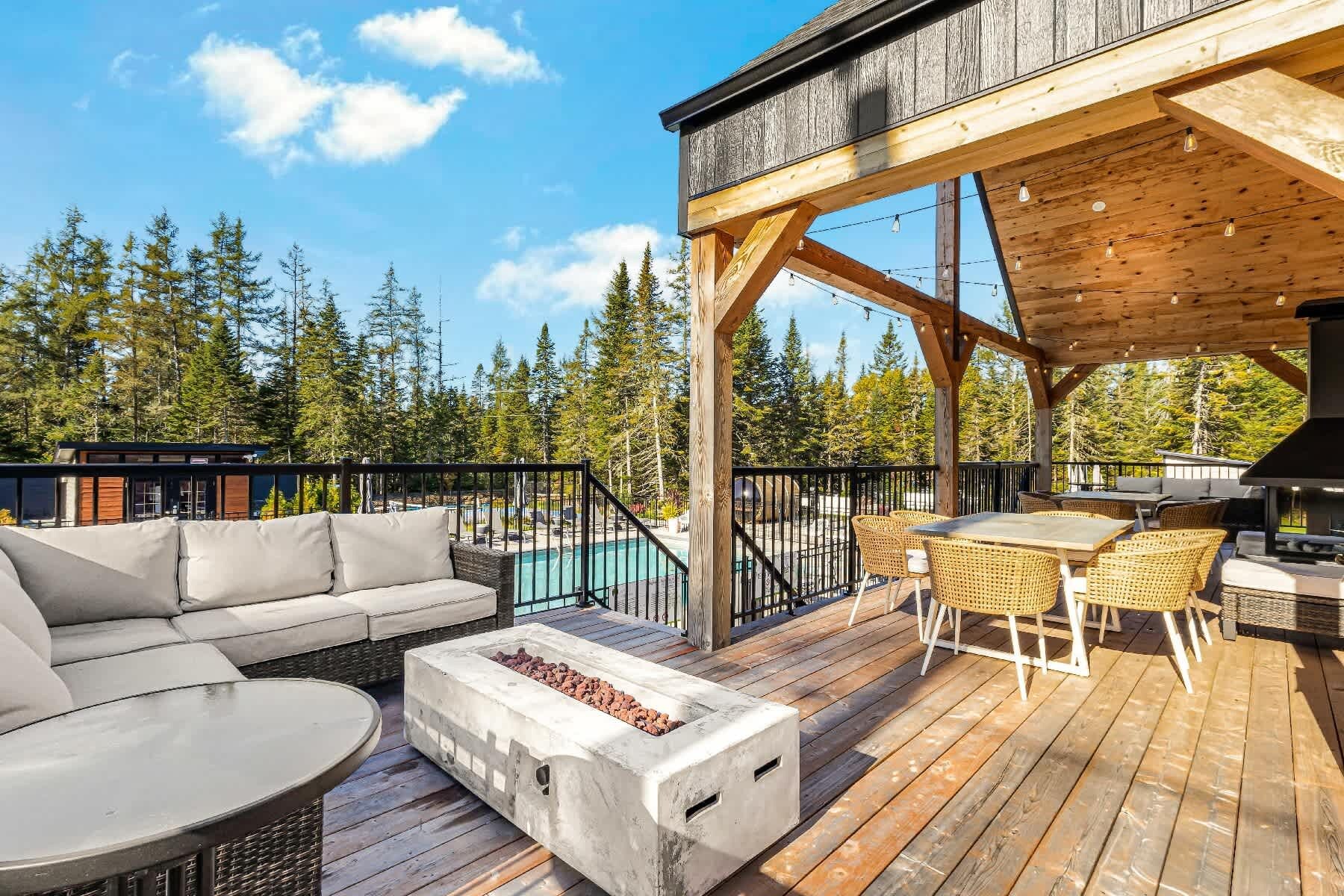 A wooden deck with outdoor furniture, a barbecue grill, and a pool.