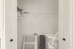 Ein weißes Zimmer mit einem weißen Kleiderschrank, einem weißen Stuhl und einer weißen Regaleinheit.