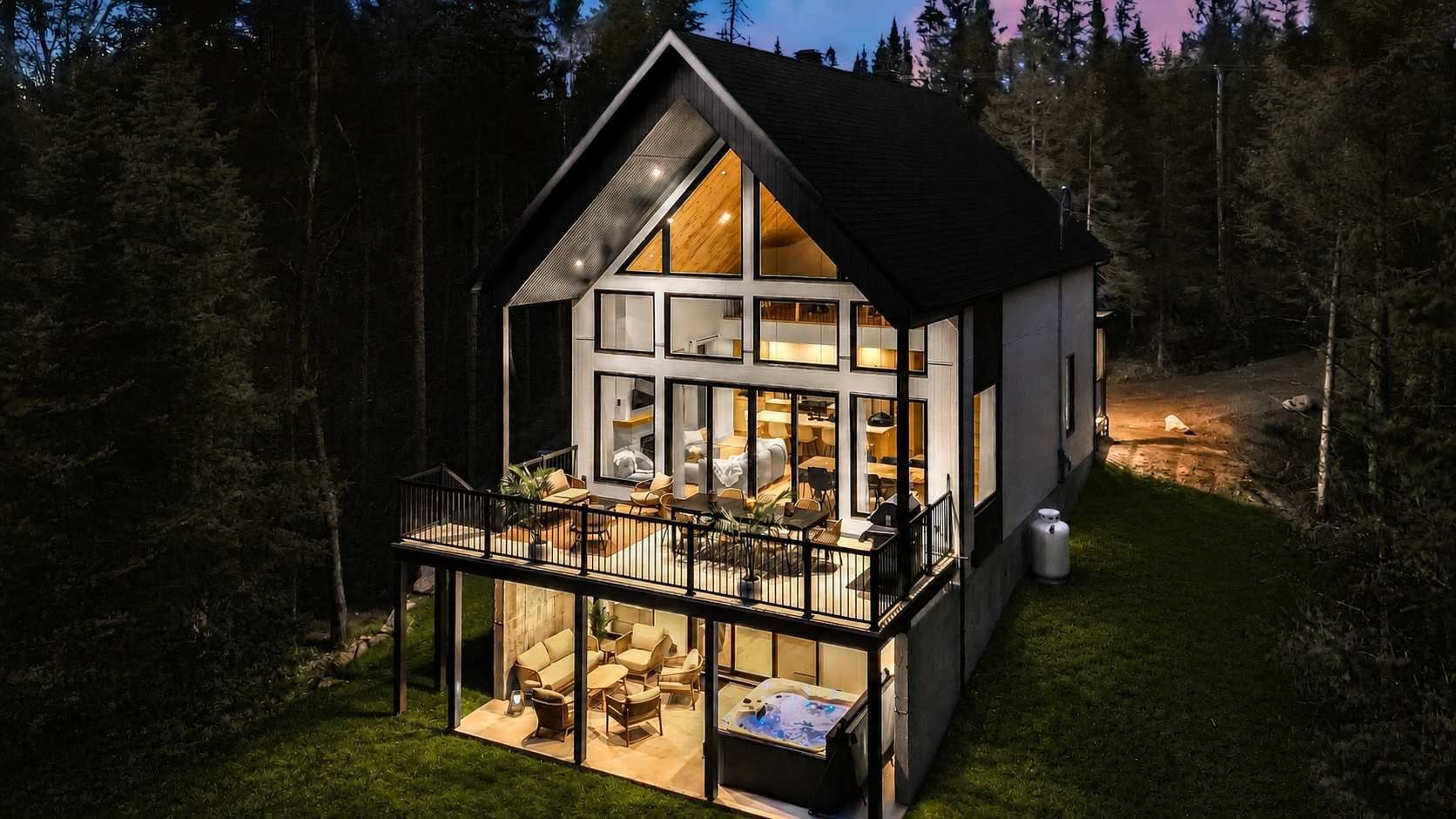 Une maison moderne dotée d’un balcon, de grandes fenêtres et d’un intérieur bien éclairé.