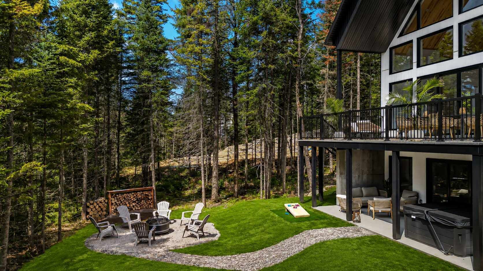 A modern house with a deck, outdoor seating, and a fire pit.