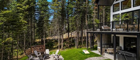 A modern house with a deck, outdoor seating, and a fire pit.