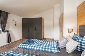 A bedroom with a bed, a wardrobe, a wall-mounted lamp, and a window with curtains. - Cabin in Inzell with swimming pool (Inzell)