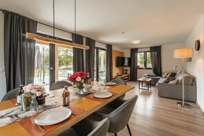 A modern living room with a dining area, a sofa, and a TV. - Cabin in Inzell with swimming pool (Inzell)