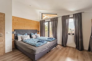 Ein Schlafzimmer mit Bett, Vorhängen, einem Holzkopfende und einem Fenster.