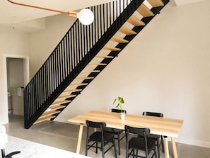 Ein modernes Interieur mit einem Holzesstisch, schwarzen Stühlen und einer schwarzen Holztreppe.