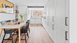 Una cucina moderna con mobili bianchi, un tavolo da pranzo con sedie e vista sull'area living.