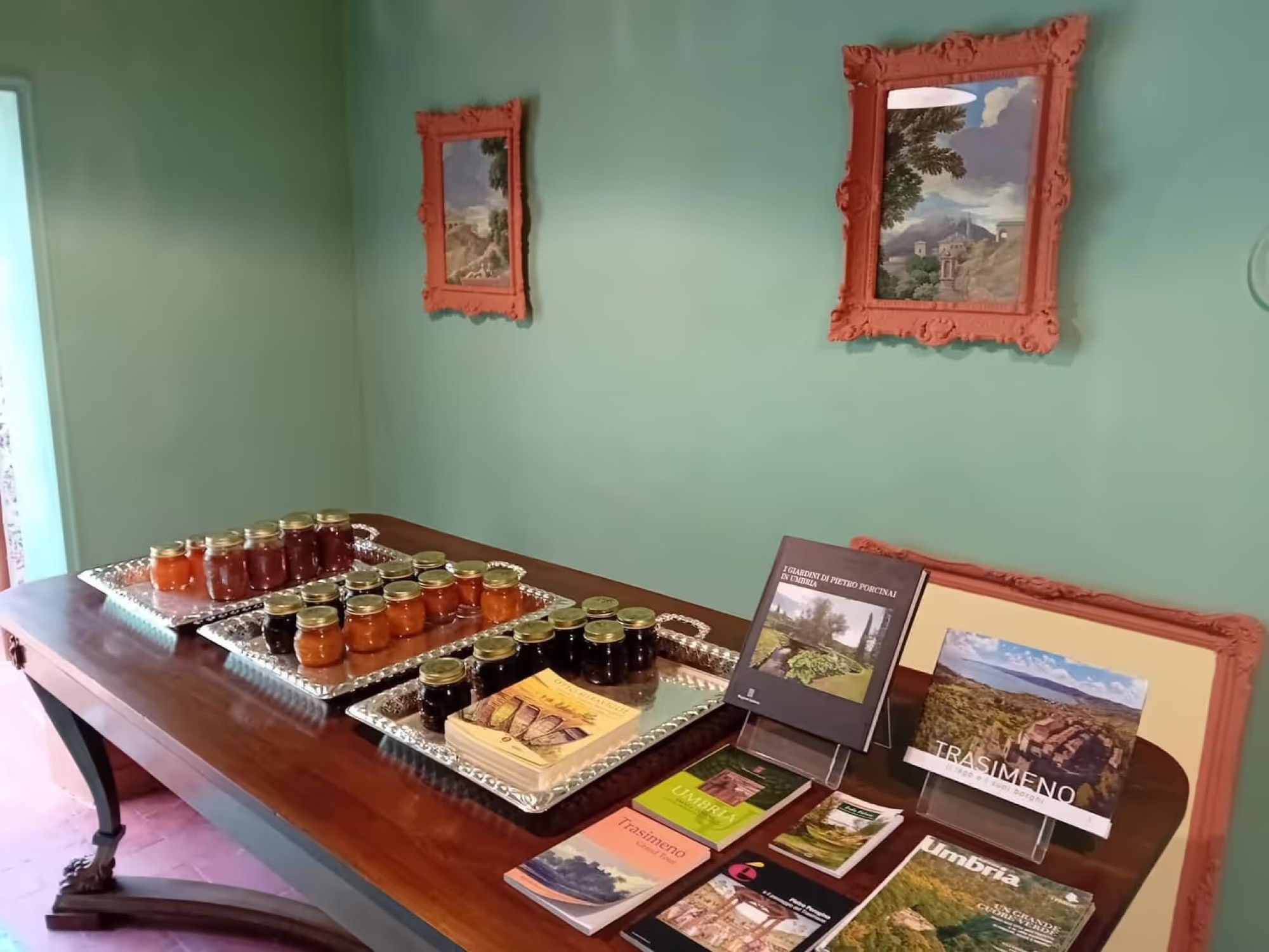 Une table sur laquelle sont disposés des pots de confitures et des livres, avec des photos encadrées accrochées au mur derrière.
