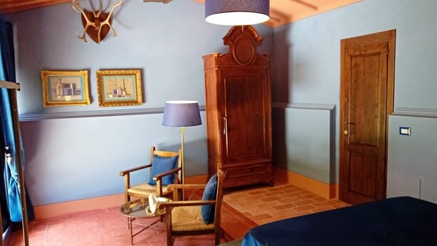 Una habitación con una cama, dos sillas, un armario y una lámpara fijada a la pared.