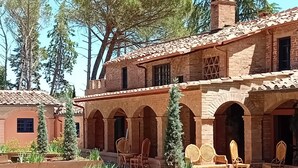 Un patio con un edificio de ladrillo, mobiliario exterior y follaje.