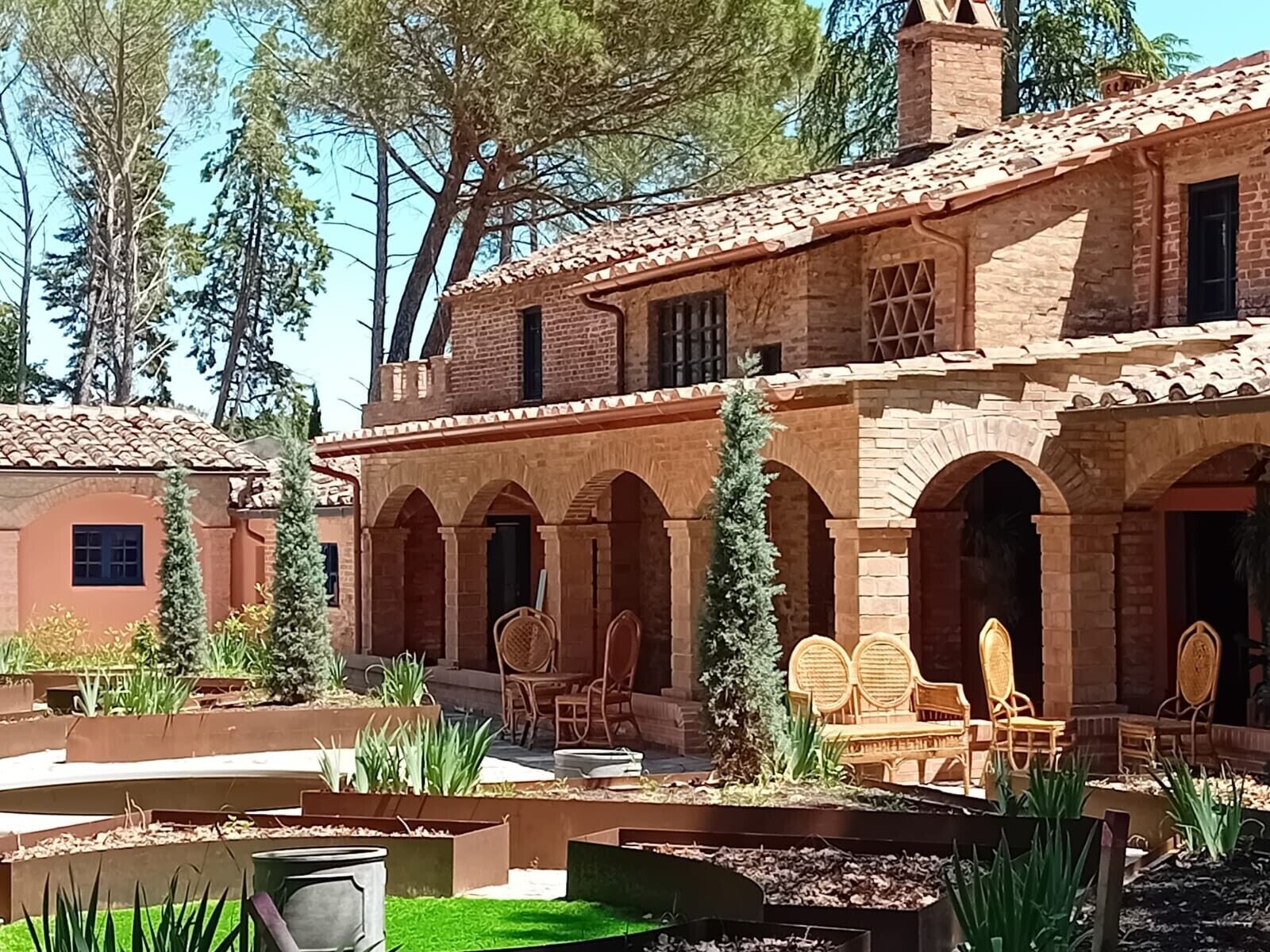 Une cour avec un bâtiment en briques, des sièges en plein air et de la verdure.