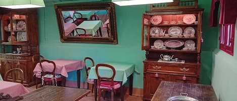 Un espace repas avec des tables et des chaises en bois, ainsi qu’un buffet contenant de la vaisselle.