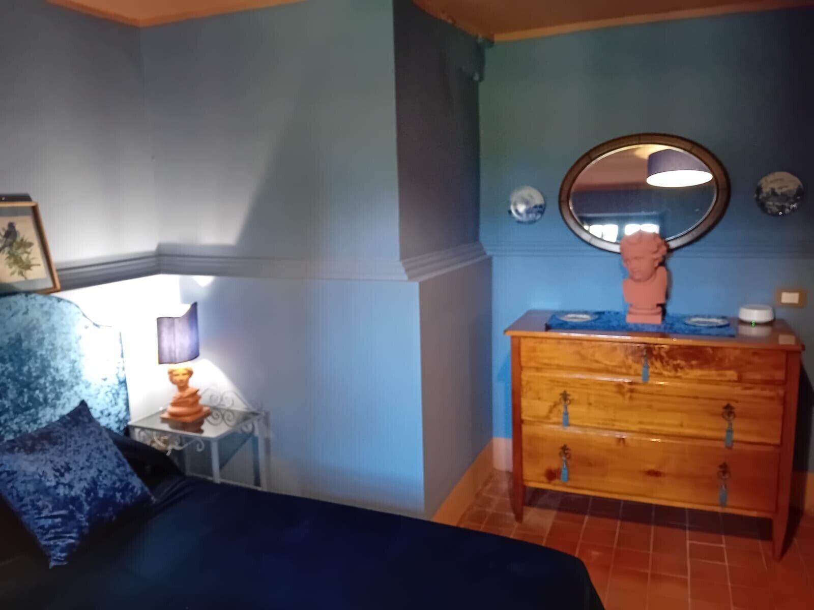 Ein Zimmer mit einem Bett, einem Schminktisch, einem Spiegel und einem kleinen Tisch mit einer Lampe.