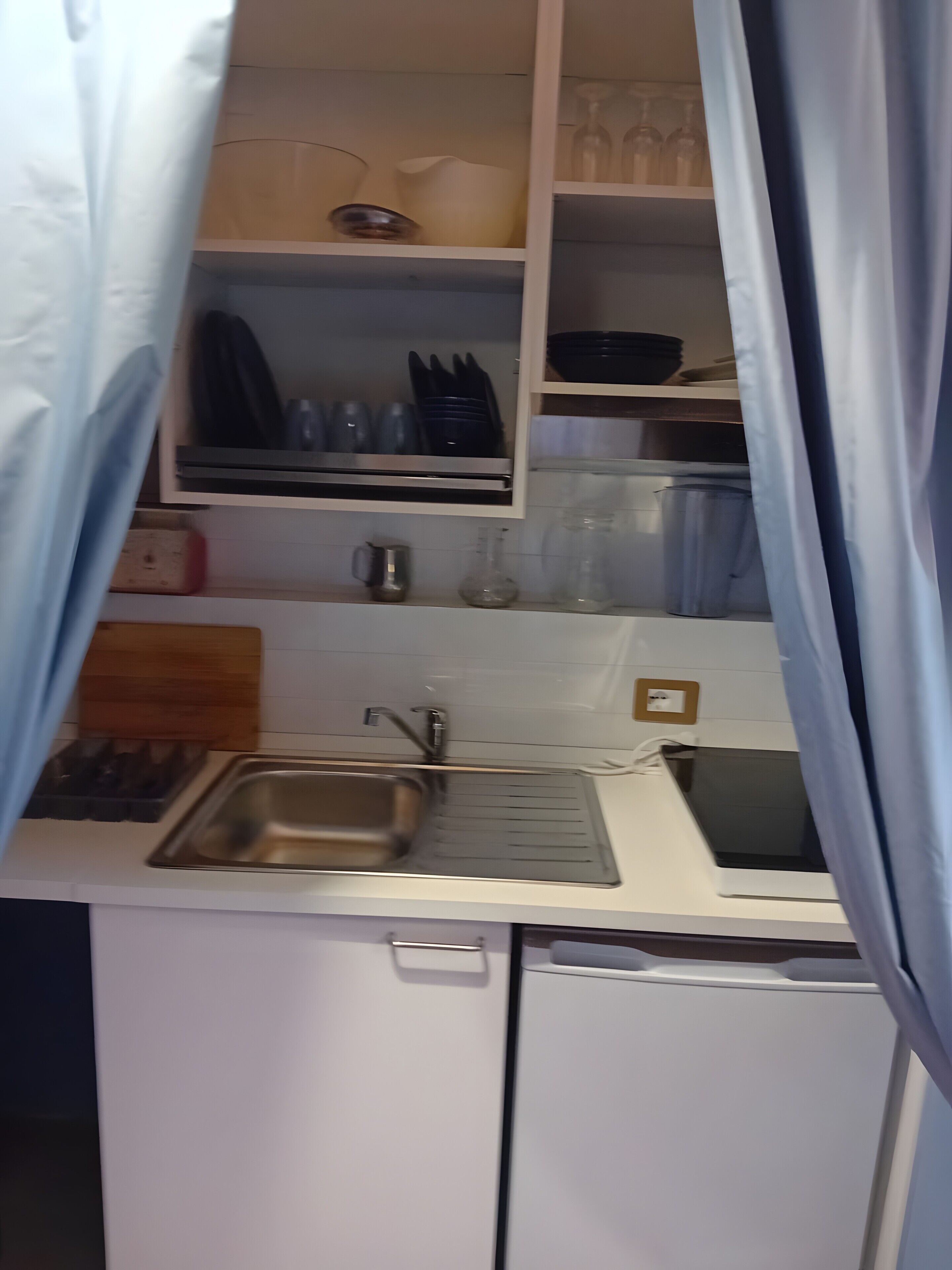 Une petite cuisine équipée d’un évier, d’une cuisinière et de placards contenant de l’ustensile de cuisine.
