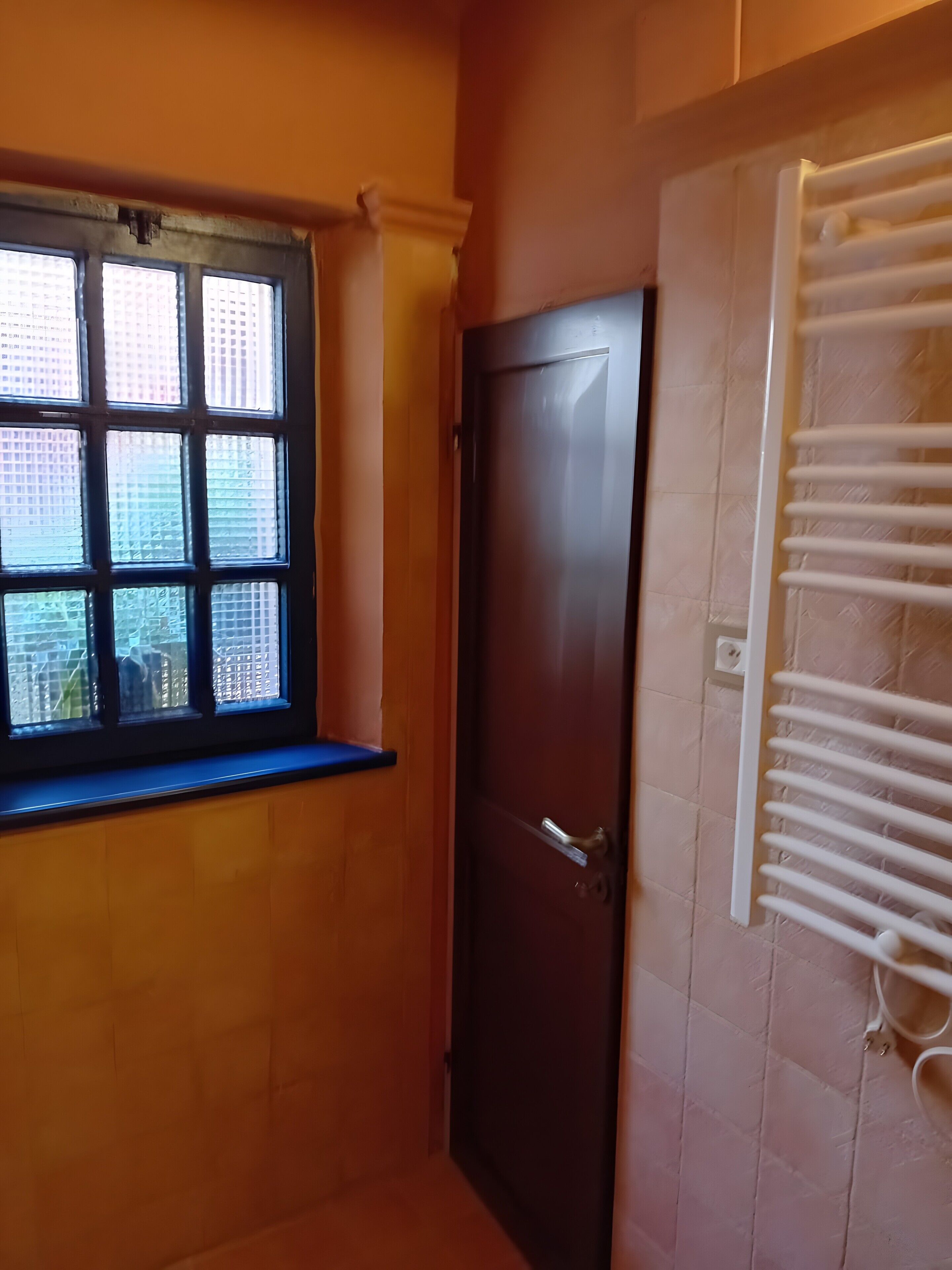 Een kamer met een raam, een deur en een radiator.