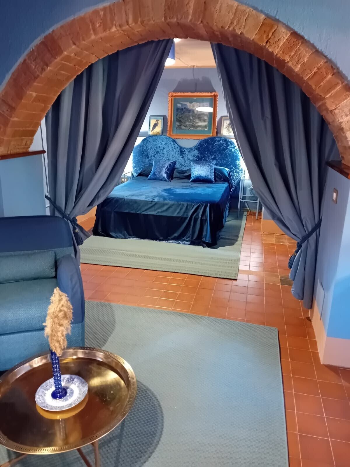 Una habitación con una cama, un sofá azul y una pequeña mesa con un adorno.