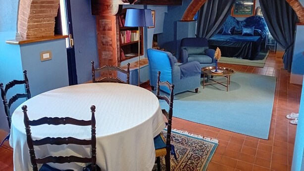 A cozy room with a dining table, chairs, a sofa, and a bed. - Suite Apartment 4 – Castel Brio Charming Resort in Castiglion del Lago (Castiglione del Lago)