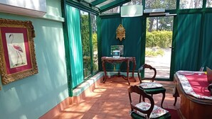A conservatory with a tiled floor, a table with chairs, a clock, and a framed picture on the wall. - Suite Apartment 4 – Castel Brio Charming Resort in Castiglion del Lago (Castiglione del Lago)