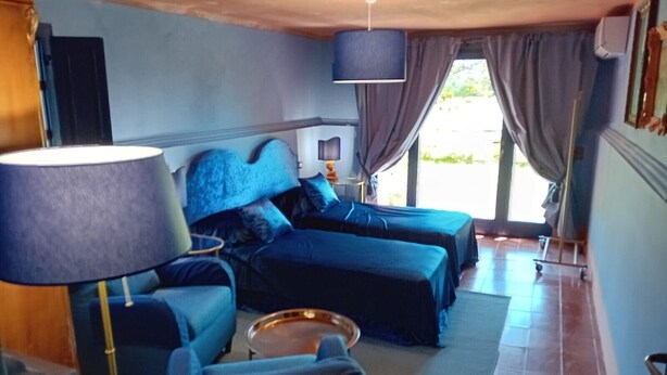 Una habitación con cama, sofá, lámpara y vistas al exterior.