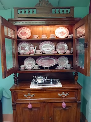 Un mueble de madera con puertas de cristal que exhibe varios artículos de cerámica.