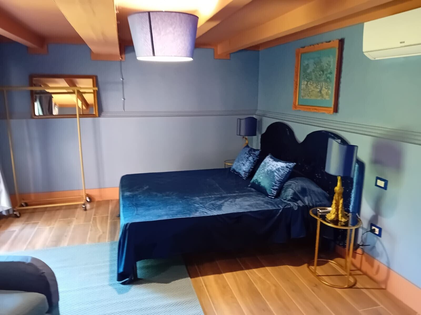 Une chambre à coucher avec un lit, une table de chevet, une lampe et un miroir au mur.