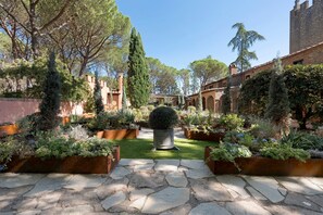 A courtyard with stone pathways, potted plants, and a central tree. - Room 'Camera 5 - Castel Brio' with Shared Pool, Wi-Fi and Air Conditioning (Castiglione del Lago)