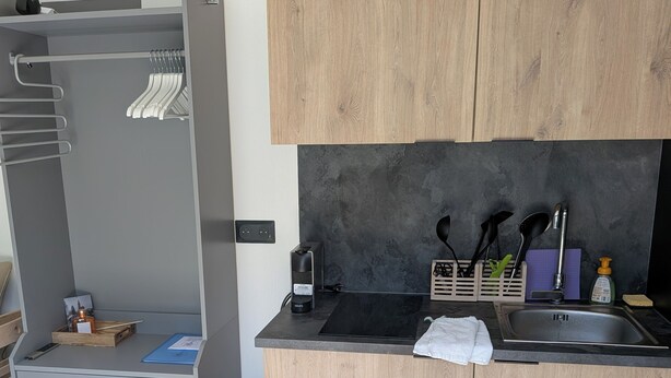 A compact kitchen with wooden cabinets, a black countertop, and a built-in sink.