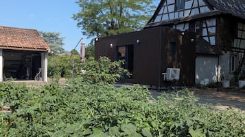 A traditional half-timbered house with a modern extension, surrounded by a vegetable garden.