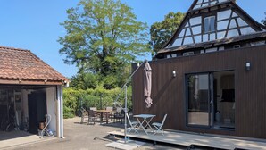 A modern building with a wooden facade, a covered outdoor seating area, and a garage. - Detached studio apartment with a garden, air conditioning, and a garage (Gries)