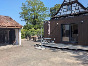 Ein modernes Gebäude mit Holzfassade, einer überdachten Außenbereich-Sitzgelegenheit und einer Garage.