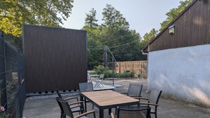 An outdoor patio with a table and chairs, surrounded by a fence and a building. - Detached studio apartment with a garden, air conditioning, and a garage (Gries)