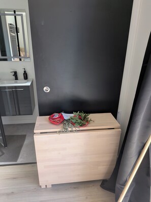 A small wooden cabinet with a mirror above it, a sink with a faucet, and a door with a lock.