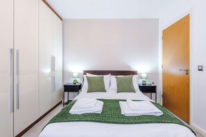A hotel room with a bed, two bedside tables, a wardrobe, and a door. - Luxury 2BR Altrincham 15m to MAN Near Market (Altrincham)