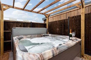 A hot tub under a wooden pergola with a wooden fence in the background. - Luxury 6BR Beach House Hot Tub Sea View (Cromer)