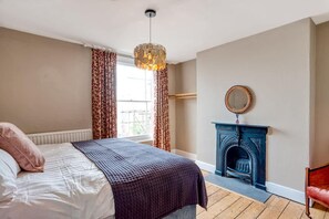 Ein Schlafzimmer mit Bett, Kamin und einem fenster mit Vorhängen.