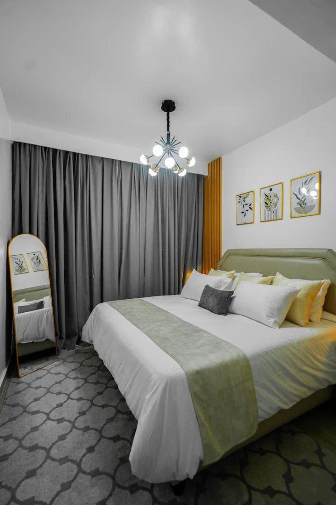 Quarto de hotel com cama, espelho, lustre e obras de arte na parede.