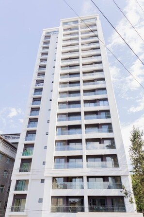 A high-rise building with multiple balconies and windows. - New Luxury Furnish 1BR @Kilimani w/ Pool, Sauna & Gym | Walk to Yaya & Dining (Nairobi)