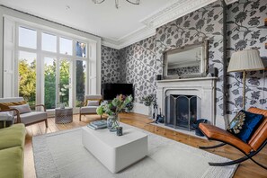 A spacious living room with a fireplace, large windows, and a modern sofa set. - Luxury 7 Bed Herts Stay Cinema Hot Tub (Hertford)