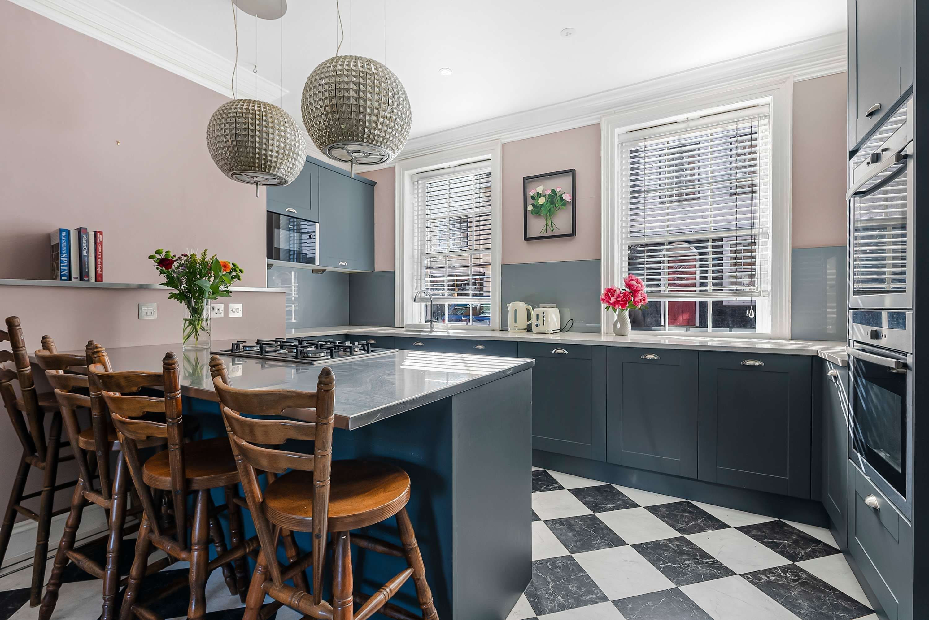 A modern kitchen with a central island, wooden chairs, and a checkered floor.