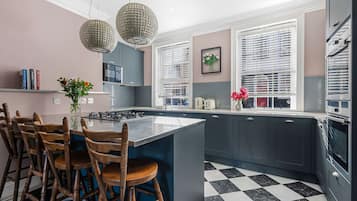 A modern kitchen with a central island, wooden chairs, and a checkered floor.