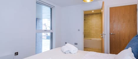 Habitació d'hotel amb un llit, una finestra, una porta i una làmpada al sostre.