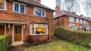 A brick house with a front door, a window with a view of the interior, and a small garden area. - Large 3BR Near Airport Hospital Free Parking (Manchester)