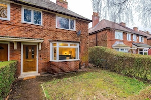 A brick house with a front door, a window with a view of the interior, and a small garden area. - Large 3BR Near Airport Hospital Free Parking (Manchester)