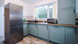 A kitchen with a refrigerator, microwave, and cabinets. - Large 3BR Near Airport Hospital Free Parking (Manchester)