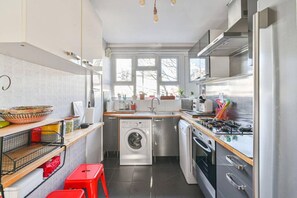 A compact kitchen with a washing machine, oven, and a small dining area. - 2BR Greenwich 2m to DLR 8m to London Bridge (London)