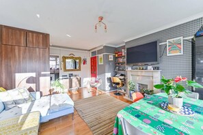 A modern living room with a sofa, a dining table, a TV, and a fireplace. - 2BR Greenwich 2m to DLR 8m to London Bridge (London)