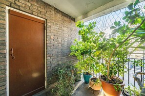 A brick wall with a brown door, potted plants on a balcony, and a chain-link fence. - 2BR Greenwich 2m to DLR 8m to London Bridge (London)